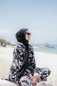 Woman wearing sunglasses sitting at beach