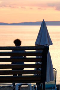 Rear view of man sitting on seat at beach