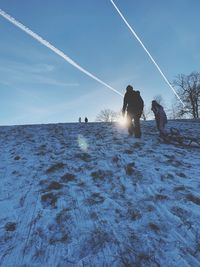 People on snow covered land by sea against sky