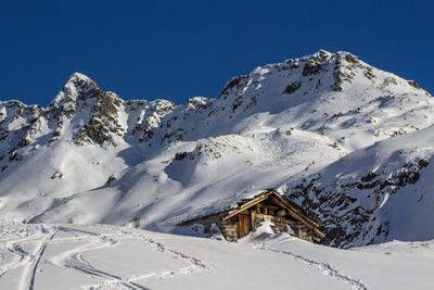 Low angle view of snowcapped mountains against clear blue sky