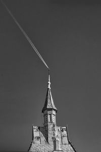 Low angle view of building against clear sky and an airplane's trail