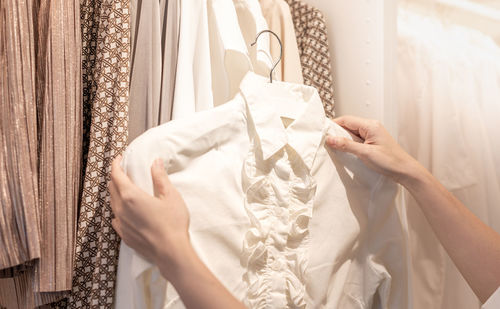 Female hand choosing clothes for checked pattern cotton polo shirt on the rack in a cloth shop.