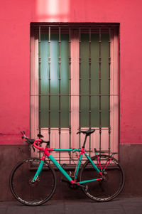 Bicycle parked against red window