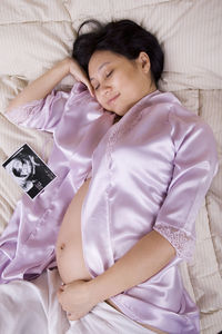 High angle view of pregnant woman sleeping on bed