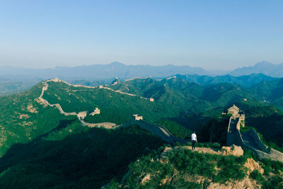 Rear view of man standing on mountain against clear sky