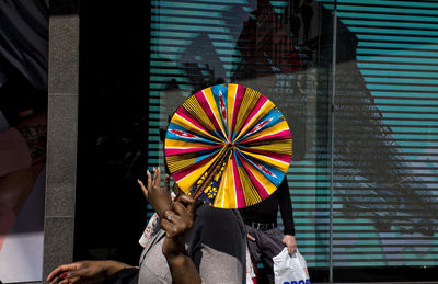 Low section of people holding multi colored umbrella