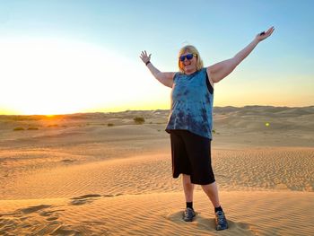 Full length of woman standing on landscape during sunset