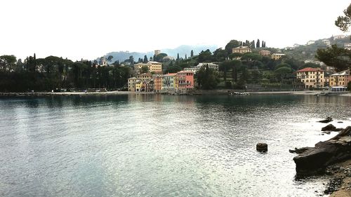 Houses by river against clear sky