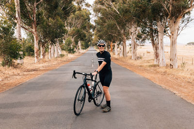 Woman standing on bicycle at road