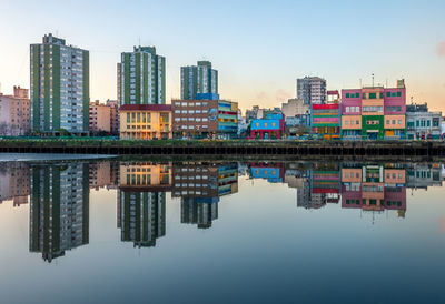 Reflection of buildings in river against sky