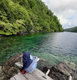 Girl sitting on rock by lake