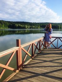 Woman standing on pier over lake