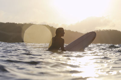 Female surfer in the ocean at sunset