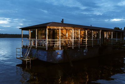 House by lake against sky