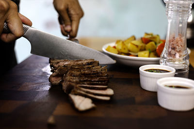 Cropped hand of man preparing food on table