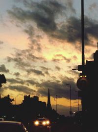 Cars on road against cloudy sky