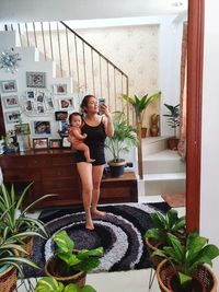 Woman standing by potted plants at home