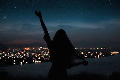 Silhouette woman standing against sky at night