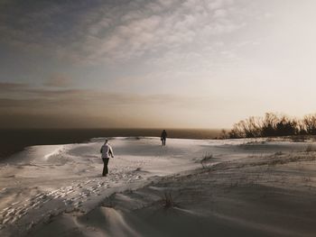 People on snow covered land against sky