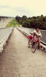 Bicycle on railing by river against sky