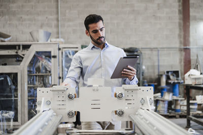 Engineer using tablet pc and operating machine in industry