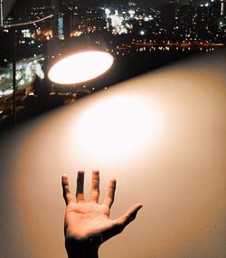 Human hand against illuminated light at night