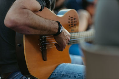 Midsection of man playing guitar