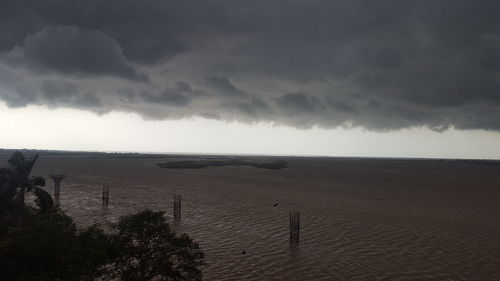 View of calm beach against cloudy sky