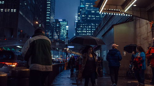 People walking on street in city during rainy season