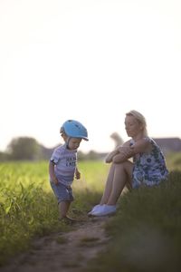 Side view of mother and daughter on field