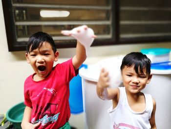 Portrait of happy brothers playing with soap sud