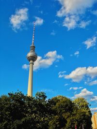 Low angle view of communications tower against cloudy sky