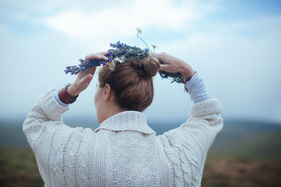 Rear view of woman holding hands against sky