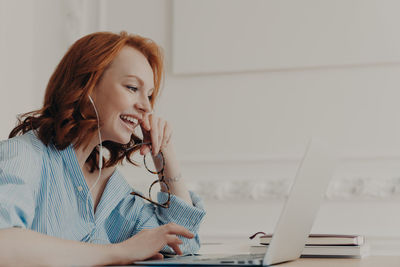 Young woman using phone while sitting on table