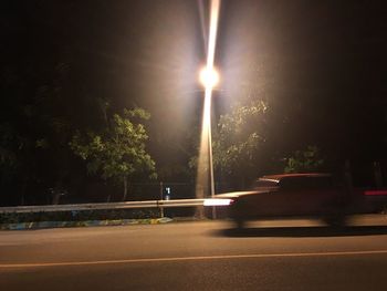 Illuminated road against sky at night