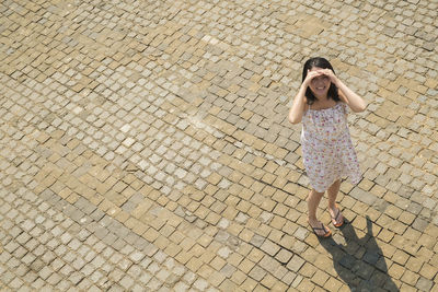 High angle portrait of woman standing on cobble footpath