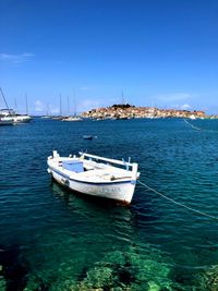 Sailboats moored in sea against clear blue sky