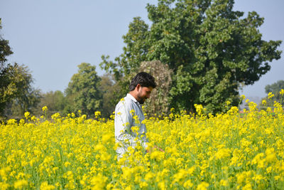 Young indian farmer at black mustard field