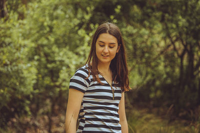 Mid adult woman standing against trees