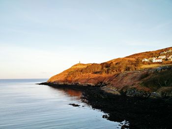 Scenic view of cliff by sea against sky