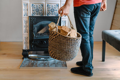 Person holding firewood basket by fireplace