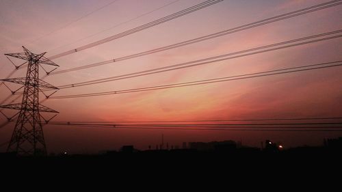 Low angle view of silhouette electricity pylon against sky during sunset