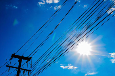 Low angle view of power lines against blue sky