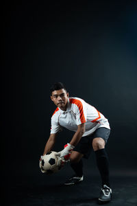 Man playing soccer ball against black background
