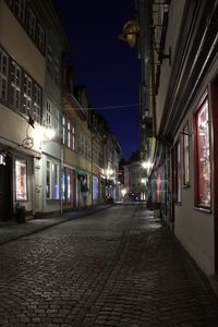 Illuminated street amidst buildings at night