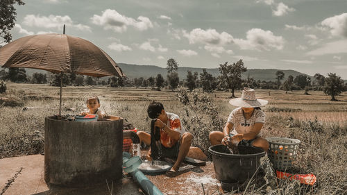 People sitting on barbecue grill against sky