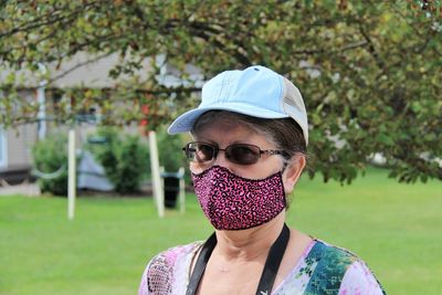 Portrait of young woman wearing sunglasses standing against plants