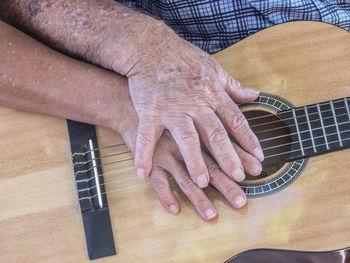 Midsection of senior couple with hands on guitar