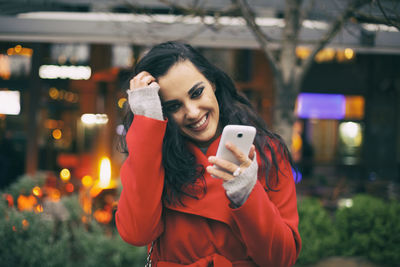 Portrait of young woman using mobile phone in city