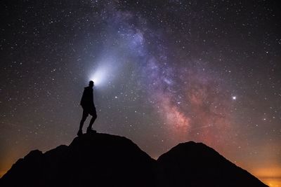 Silhouette woman standing on mountain against sky at night